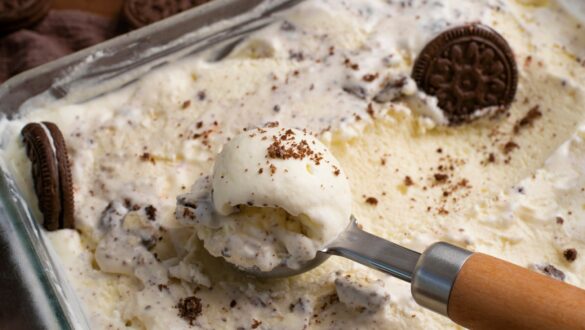 Смачний десерт у вигляді морозива з кусочками печива Oreo, оформлений збитими вершками та посипаними шоколадними крихтами, подається порційною ложкою.