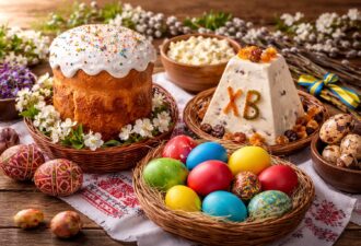 Традиційний великодній стіл у українському стилі: паска з глазур’ю, сирна пасха, різнокольорові крашанки та писанки на вишитому рушнику, дерев’яний стіл і весняний декор.