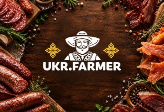 Логотип UKR.FARMER по центру обкладинки на темному дерев’яному фоні, по краях — копчені ковбаси, нарізане в’ялене м’ясо, м’ясні снеки, розмарин, часник і спеції.